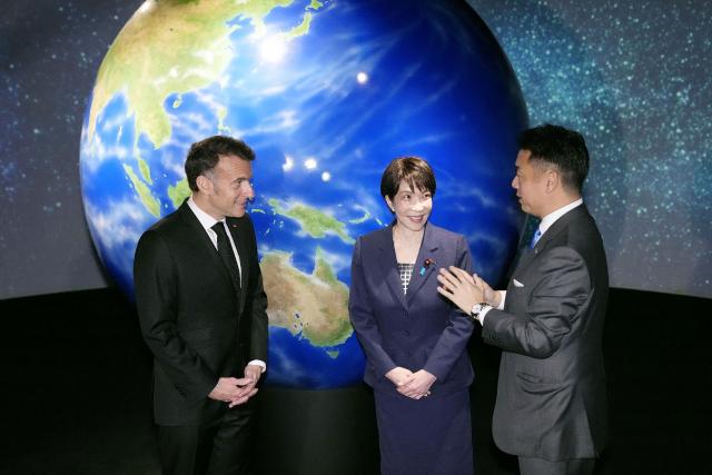 France's President Emmanuel Macron (L) and Japan's Prime Minister Sanae Takaichi (C) inspect the space company Astroscale in Tokyo on April 2, 2026. (Photo by JAPAN POOL / JIJI PRESS / AFP) / Japan OUT