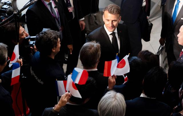 French President Emmanuel Macron (top-C) speaks with people after visiting Astroscale, a space venture company, in Tokyo on April 2, 2026. (Photo by Jeanne ACCORSINI / POOL / AFP)