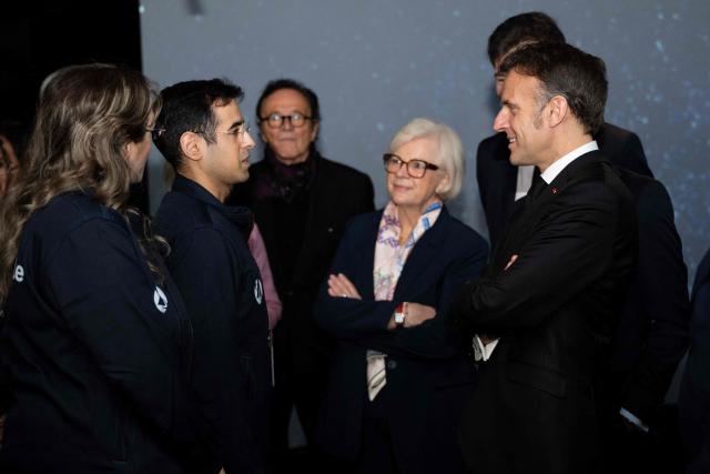 French President Emmanuel Macron (R) and French Minister for the Armed Forces and Veterans Affairs Catherine Vautrin (2nd-R) speak with people after visiting Astroscale, a space venture company, in Tokyo on April 2, 2026. (Photo by Jeanne ACCORSINI / POOL / AFP)