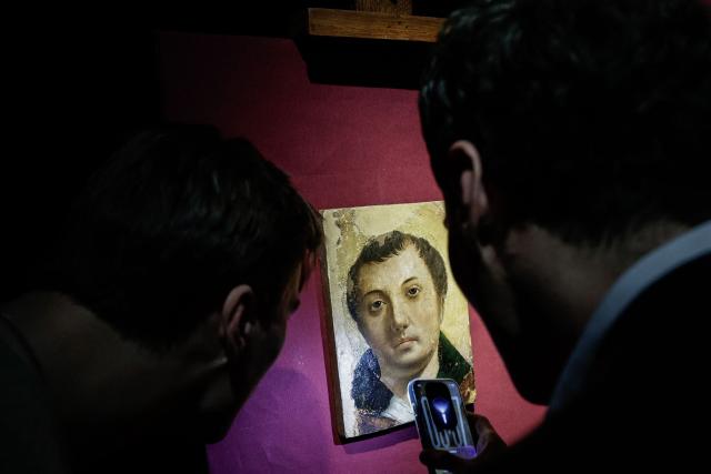 Two employees look at a painting entitled "Face of a Young Saint" by artist Antonello da Messina ahead of its auction at Hotel Drouot auction house in Paris on April 2, 2026. (Photo by STEPHANE DE SAKUTIN / AFP)