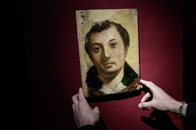 An employee handles a painting entitled "Face of a Young Saint" by artist Antonello da Messina ahead of its auction at Hotel Drouot auction house in Paris on April 2, 2026. (Photo by STEPHANE DE SAKUTIN / AFP)