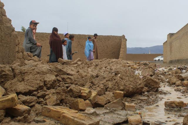 Residents gather beside the collapsed mud wall of a house during heavy rains and a storm in Chaman near the Pakistan-Afghanistan border on April 2, 2026. Heavy rain and storms have killed at least 45 people over the past few days across Afghanistan and Pakistan, as per disaster officials in both countries. (Photo by Abdul BASIT / AFP)