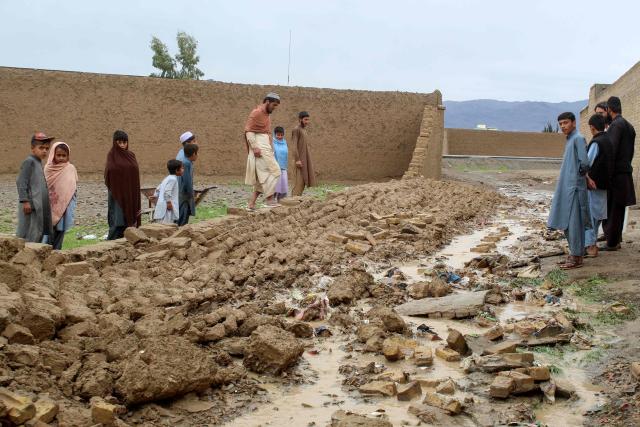 Residents gather beside the collapsed mud wall of a house during heavy rains and a storm in Chaman near the Pakistan-Afghanistan border on April 2, 2026. Heavy rain and storms have killed at least 45 people over the past few days across Afghanistan and Pakistan, as per disaster officials in both countries. (Photo by Abdul BASIT / AFP)