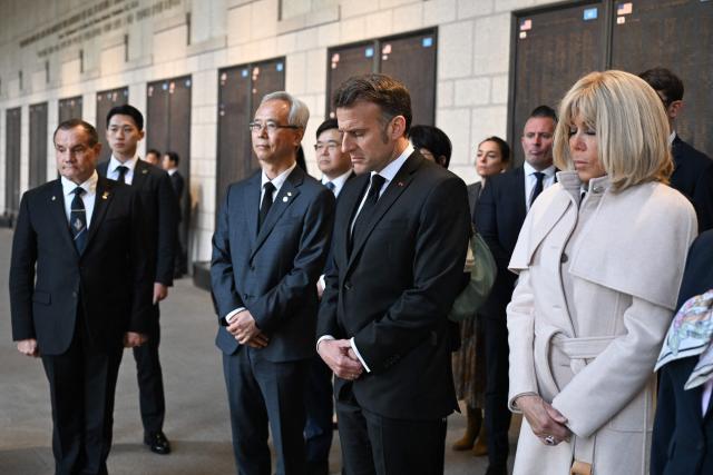 French President Emmanuel Macron and his wife Brigitte Macron (R) look at a monument with the names of fallen French soldiers who fought for South Korea during the 1950-53 Korean War, during a visit at the War Memorial of Korea in Seoul on April 2, 2026. (Photo by Jeanne Accorsini / POOL / AFP)