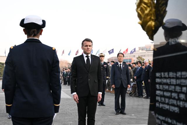 French President Emmanuel Macron (C) attends a wreath-laying ceremony to pay tribute to fallen French soldiers who fought for South Korea during the 1950-53 Korean War, during a visit to the War Memorial of Korea in Seoul on April 2, 2026. (Photo by Jeanne Accorsini / POOL / AFP)