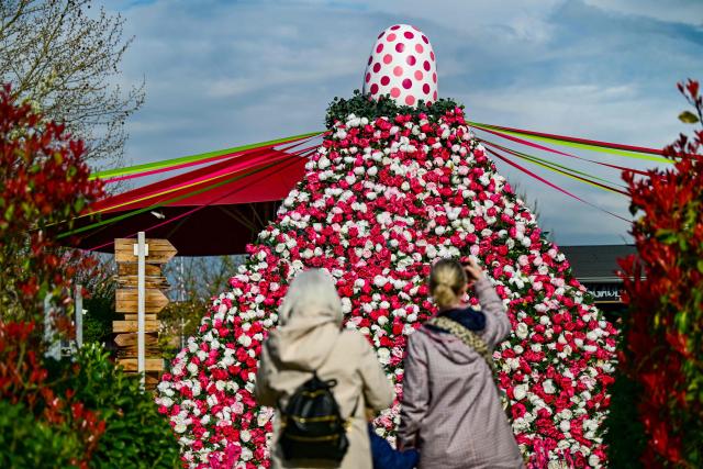 Women take a photo of a giant flower pyramid at the 'Gertrudenhof' adventure farm for children in Huerth, western Germany on April 2, 2026, ahead of the Easter celebrations. (Photo by Ina FASSBENDER / AFP)