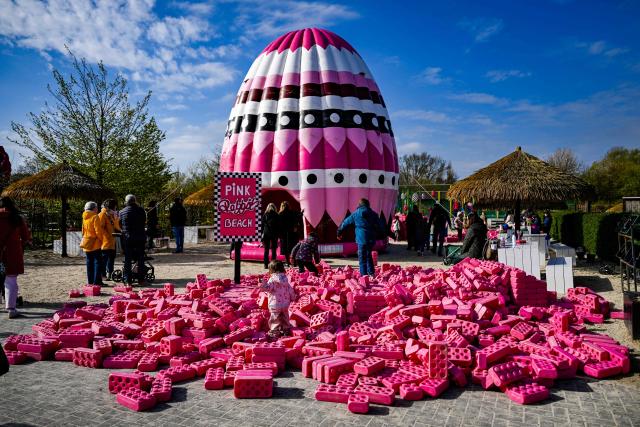 A girl plays in front of an oversized Easter egg at the 'Gertrudenhof' adventure farm for children in Huerth, western Germany on April 2, 2026, ahead of the Easter celebrations. (Photo by Ina FASSBENDER / AFP)