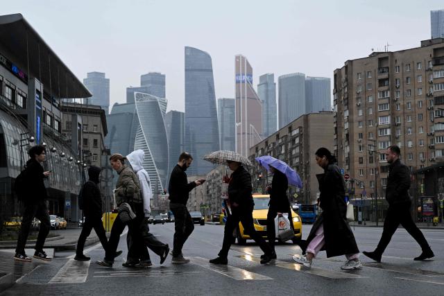 People cross the Bolshaya Dorogomilovskaya street with the Moskva City business center in the background in Moscow on April 2, 2026. (Photo by Igor IVANKO / AFP)