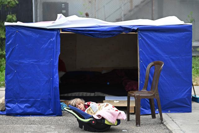 TOPSHOT - A displaced young toddler sleeps at the entrance of his tent at an unofficial camp for displaced people on Beirut's waterfront area on April 2, 2026. Lebanon was drawn into the Middle East war on March 2 when Tehran-backed militant group Hezbollah launched attacks on Israel to avenge the killing of the Iranian leader. Israel has responded with broad strikes across Lebanon and a ground offensive. (Photo by Joseph EID / AFP)