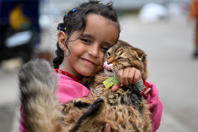TOPSHOT - A displaced girl cuddles her cat at the entrance of a tent at an unofficial camp for displaced people on Beirut's waterfront area on April 2, 2026. Lebanon was drawn into the Middle East war on March 2 when Tehran-backed militant group Hezbollah launched attacks on Israel to avenge the killing of the Iranian leader. Israel has responded with broad strikes across Lebanon and a ground offensive. (Photo by Joseph EID / AFP)