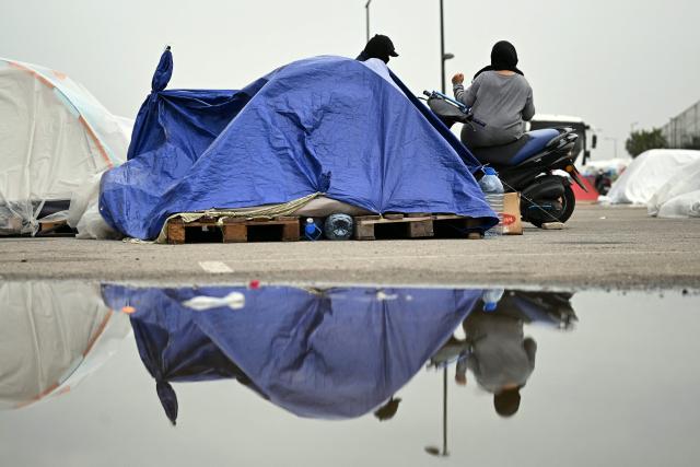 Displaced women sit at the entrance of a tent at an unofficial camp for displaced people on Beirut's waterfront area on April 2, 2026. Lebanon was drawn into the Middle East war on March 2 when Tehran-backed militant group Hezbollah launched attacks on Israel to avenge the killing of the Iranian leader. Israel has responded with broad strikes across Lebanon and a ground offensive. (Photo by Joseph EID / AFP)