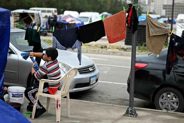 A displaced young boy washes his clothes at the entrance of a tent at an unofficial camp for displaced people on Beirut's waterfront area on April 2, 2026. Lebanon was drawn into the Middle East war on March 2 when Tehran-backed militant group Hezbollah launched attacks on Israel to avenge the killing of the Iranian leader. Israel has responded with broad strikes across Lebanon and a ground offensive. (Photo by Joseph EID / AFP)