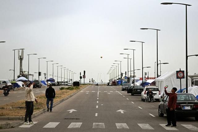 Displaced young boys play near tents at an unofficial camp for displaced people on Beirut's waterfront area on April 2, 2026. Lebanon was drawn into the Middle East war on March 2 when Tehran-backed militant group Hezbollah launched attacks on Israel to avenge the killing of the Iranian leader. Israel has responded with broad strikes across Lebanon and a ground offensive. (Photo by Joseph EID / AFP)