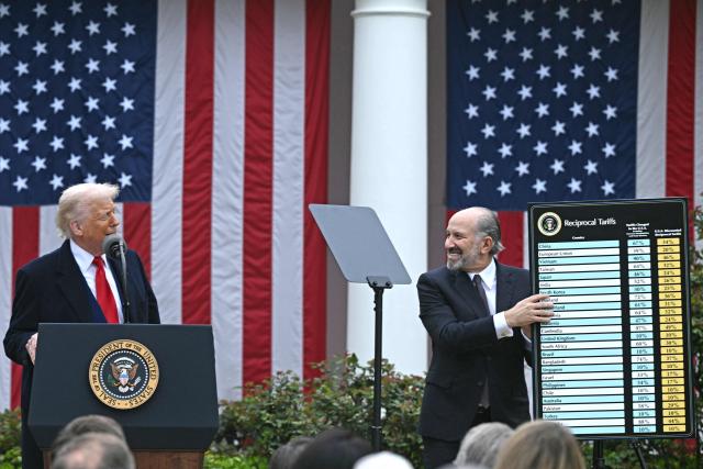 (FILES) US President Donald Trump delivers remarks on reciprocal tariffs as US Secretary of Commerce Howard Lutnick holds a chart during an event in the Rose Garden entitled "Make America Wealthy Again" at the White House in Washington, DC, on April 2, 2025. The US trade deficit widened in Februart 2026 but less than analysts expected, government data showed on April 2, 2026, a year since President Donald Trump unleashed sweeping tariffs on virtually all trading partners. The overall gap expanded 4.9 percent to $57.3 billion as both imports and exports climbed, said the Commerce Department. Turmoil over Trump's tariff agenda, however, looks set to continue swaying trade flows in the world's biggest economy. (Photo by Brendan SMIALOWSKI / AFP)
