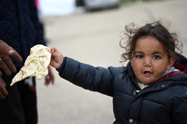 A displaced young girl holds a loaf of bread at an unofficial camp for displaced people on Beirut's waterfront area on April 2, 2026. Lebanon was drawn into the Middle East war on March 2 when Tehran-backed militant group Hezbollah launched attacks on Israel to avenge the killing of the Iranian leader. Israel has responded with broad strikes across Lebanon and a ground offensive. (Photo by Joseph EID / AFP)