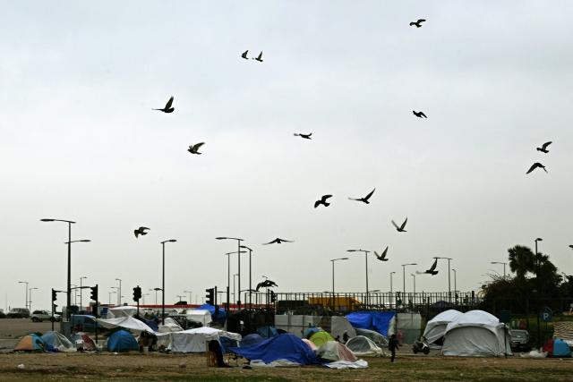 Pigeons fly over tents at an unofficial camp for displaced people on Beirut's waterfront area on April 2, 2026. Lebanon was drawn into the Middle East war on March 2 when Tehran-backed militant group Hezbollah launched attacks on Israel to avenge the killing of the Iranian leader. Israel has responded with broad strikes across Lebanon and a ground offensive. (Photo by Joseph EID / AFP)