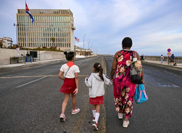 A woman with two girls walks past the US embassy in Havana on April 2, 2026. (Photo by YAMIL LAGE / AFP)