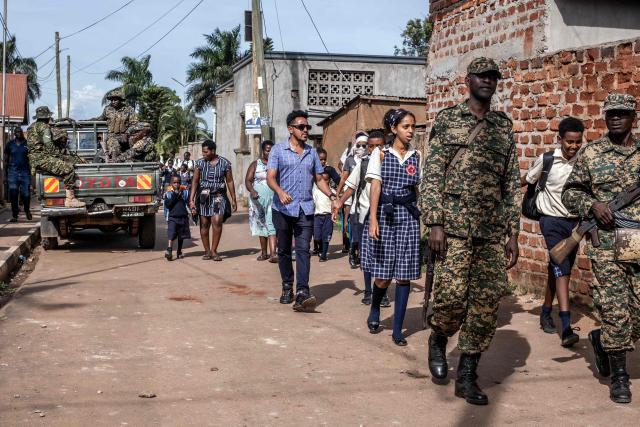 Ugandan military police officers escort parents and students next to the Ggaba Early Childhood Development Program school following an attack on children in Kampala on April 2, 2026. Four children were stabbed to death on April 2, 2026 at a kindergarten in Uganda's capital, Kampala, police said.
The male suspect gained access by posing as a parent before attacking the children, who local media reported were aged between two and three. (Photo by Badru Katumba / AFP)