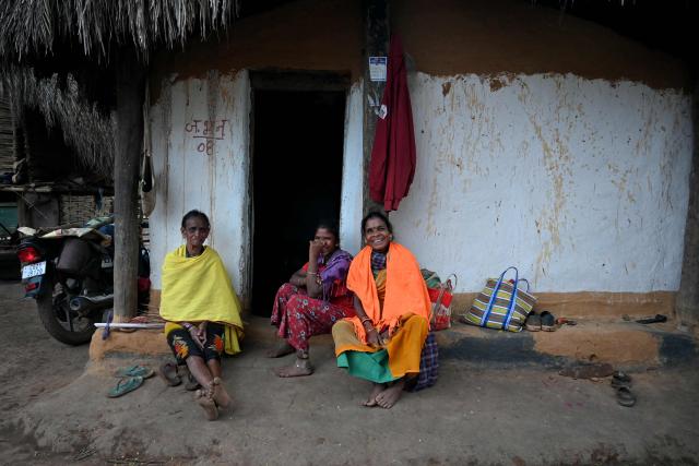 Women look on whilst they sit outside a hut in Mohandi village in Chhattisgarh on April 2, 2026. (Photo by Shammi MEHRA / AFP)
