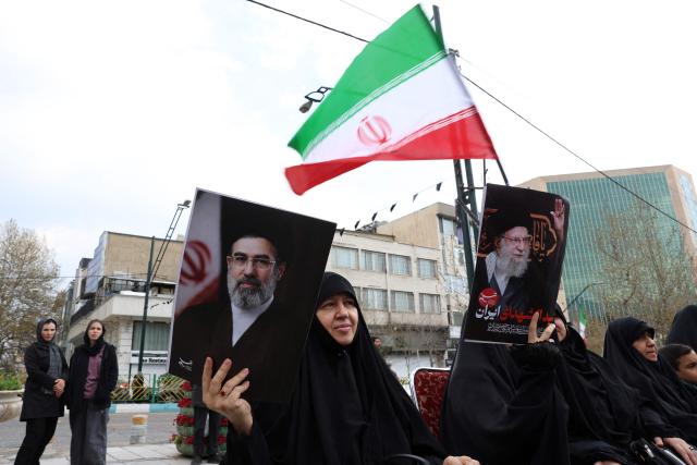 Iranian woman hold portaits of Iran's supreme leader Mojtaba Khamenei (R) and  Irans slain supreme leader Ayatollah Ali Khamenei (L) while gatheringin front of Tehran's Mellat park on April 2, 2026, during "Sizdeh Bedar" (Nature Day), the 13th day after the Nowruz Persian New Year, when people traditionally picnic outdoors with family and friends. Iran on April 2, threatened "crushing" attacks on the US and Israel, firing missiles at Tel Aviv after the US president vowed to bomb the Islamic republic "back to the Stone Ages". (Photo by AFP) / 