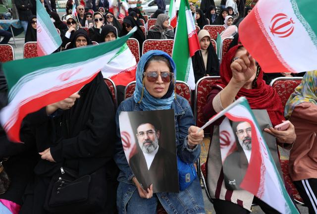 Iranian woman hold portaits of Iran's supreme leader Mojtaba Khamenei while gathering in front of Tehran's Mellat park on April 2, 2026, during "Sizdeh Bedar" (Nature Day), the 13th day after the Nowruz Persian New Year, when people traditionally picnic outdoors with family and friends. Iran on April 2, threatened "crushing" attacks on the US and Israel, firing missiles at Tel Aviv after the US president vowed to bomb the Islamic republic "back to the Stone Ages". (Photo by AFP) / 