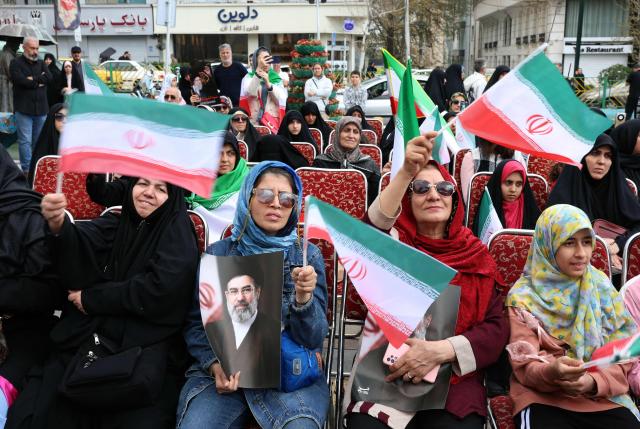 Iranian woman hold portraits of Iran's supreme leader Mojtaba Khamenei while gathering in front of Tehran's Mellat park on April 2, 2026, during "Sizdeh Bedar" (Nature Day), the 13th day after the Nowruz Persian New Year, when people traditionally picnic outdoors with family and friends. Iran on April 2, threatened "crushing" attacks on the US and Israel, firing missiles at Tel Aviv after the US president vowed to bomb the Islamic republic "back to the Stone Ages". (Photo by AFP) / 