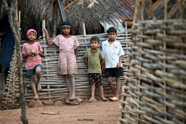 Children look on whilst they stand outside a hut in Mohandi village in Chhattisgarh on April 2, 2026. (Photo by Shammi MEHRA / AFP)
