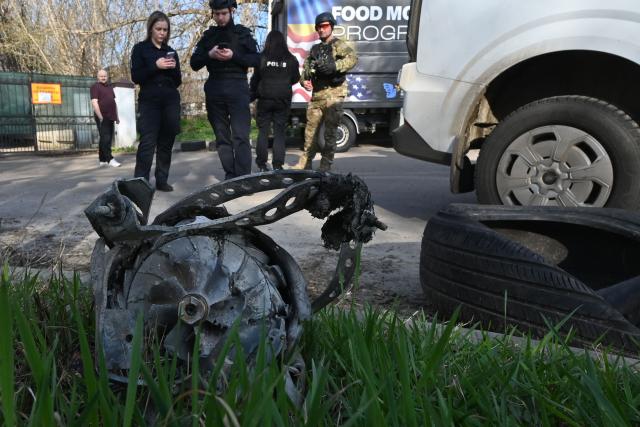 Ukrainian police stand next to a fragment of a drone in the courtyard of a residential building following an air attack in Kharkiv on April 2, 2026, amid the Russian invasion of Ukraine. (Photo by SERGEY BOBOK / AFP)