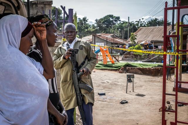 TOPSHOT - A Ugandan police officer monitors access as residents and parents gather at the entrance of the Ggaba Early Childhood Development Program school following an attack on children in Kampala on April 2, 2026. Four children were stabbed to death on April 2, 2026 at a kindergarten in Uganda's capital, Kampala, police said.
The male suspect gained access by posing as a parent before attacking the children, who local media reported were aged between two and three. (Photo by Badru Katumba / AFP)