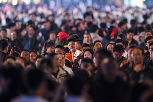 People walk on the Bund in the Huangpu district in Shanghai on April 2, 2026. (Photo by Hector RETAMAL / AFP)