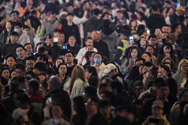 People walk on the Bund in the Huangpu district in Shanghai on April 2, 2026. (Photo by Hector RETAMAL / AFP)