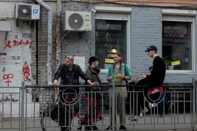 People have drinks outside a bar in a street in Kyiv on April 2, 2026, amid the Russian invasion of Ukraine. (Photo by Tetiana DZHAFAROVA / AFP)