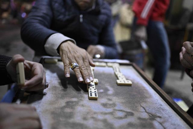 People play a game of dominos as they sit at a roadside cafe before closing in downtown Cairo on April 2, 2026. (Photo by Khaled DESOUKI / AFP)