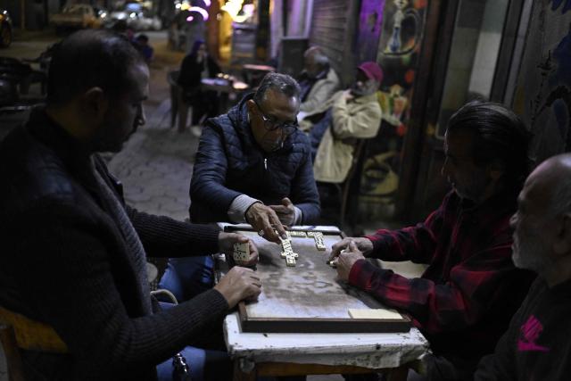 People play a game of dominos as they sit at a roadside cafe before closing in downtown Cairo on April 2, 2026. (Photo by Khaled DESOUKI / AFP)