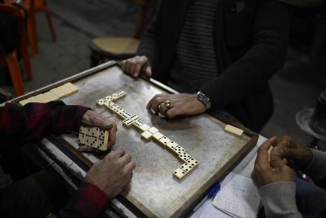 People play a game of dominos as they sit at a roadside cafe before closing in downtown Cairo on April 2, 2026. (Photo by Khaled DESOUKI / AFP)