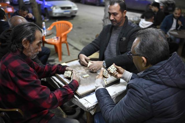People play a game of dominos as they sit at a roadside cafe before closing in downtown Cairo on April 2, 2026. (Photo by Khaled DESOUKI / AFP)