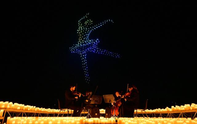 A string quartet performs as over 1,000 drones form a figure in the sky during the DroneArt show in Milan, on April 2, 2026. (Photo by Stefano RELLANDINI / AFP)