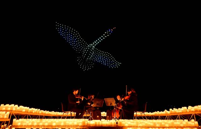 TOPSHOT - A string quartet performs as over 1,000 drones form a figure in the sky during the DroneArt show in Milan, on April 2, 2026. (Photo by Stefano RELLANDINI / AFP)
