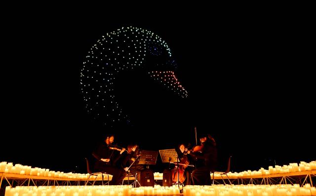A string quartet performs as over 1,000 drones form a figure in the sky during the DroneArt show in Milan, on April 2, 2026. (Photo by Stefano RELLANDINI / AFP)
