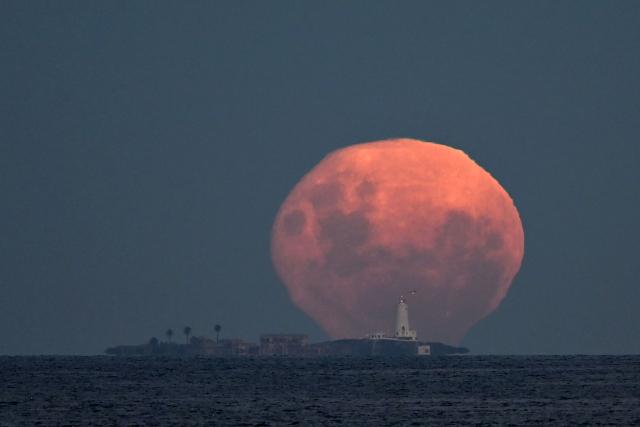 TOPSHOT - The moon in its Waning Gibbous phase rises behind Isla de Flores Island (Flowers Island) off the coast of Montevideo on April 2, 2026. (Photo by Mariana SUAREZ / AFP)