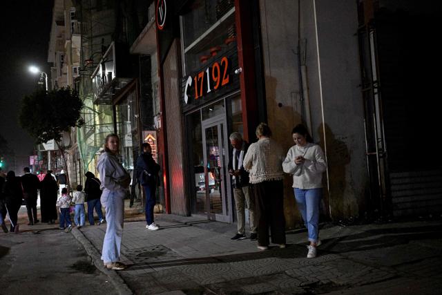 Tourists stand outside a closed restaurant in downtown Cairo on April 2, 2026. Egypt has ordered shops, restaurants and shopping malls to close from 9:00 pm from April 3, hoping to curb energy bills that have more than doubled because of the Iran war. Prime Minister Mostafa Madbouly announced the curfew and said it would last for a month initially. (Photo by Khaled DESOUKI / AFP)