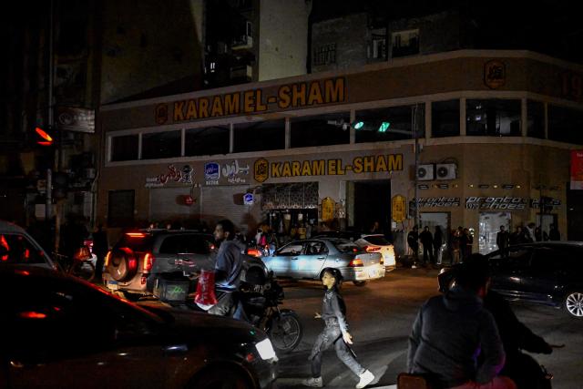 People walk past shops closed early under a government-ordered curfew aimed at reducing energy costs in downtown Cairo on April 2, 2026. Egypt has ordered shops, restaurants and shopping malls to close from 9:00 pm from April 3, hoping to curb energy bills that have more than doubled because of the Iran war. Prime Minister Mostafa Madbouly announced the curfew and said it would last for a month initially. (Photo by Khaled DESOUKI / AFP)