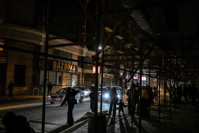 People walk past shops closed early under a government-ordered curfew aimed at reducing energy costs in downtown Cairo on April 2, 2026. Egypt has ordered shops, restaurants and shopping malls to close from 9:00 pm from April 3, hoping to curb energy bills that have more than doubled because of the Iran war. Prime Minister Mostafa Madbouly announced the curfew and said it would last for a month initially. (Photo by Khaled DESOUKI / AFP)