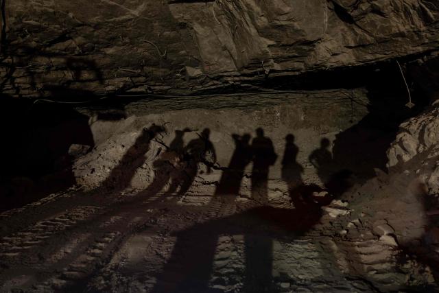 Shadows of miners are visible on the wall of a mining face more than 1,000 meters underground in the Polkowice–Sieroszowice copper and silver mine in southwestern Poland, owned by KGHM, a metallurgical powerhouse in the country, on March 25, 2026. Thousands of meters beneath the ground, amid suffocating heat, lies one of the keys to Poland's rumbling mining sector -- and the world economy. (Photo by Wojtek RADWANSKI / AFP)