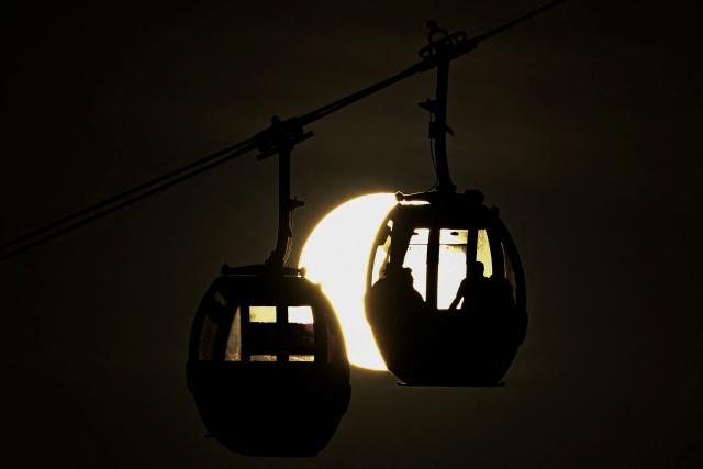 TOPSHOT - The silhouettes of two funiculars transporting tourists at El Avila (Guarairarepano) National Park are seen during sunset in Caracas on April 2, 2026. (Photo by Juan BARRETO / AFP)