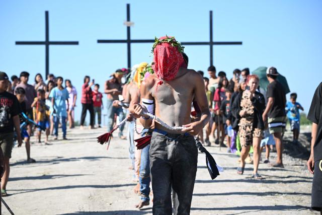 Penitents flagellate themselves as they walk along a mound with crosses prior to the annual crucifixion during the observance of Lent in the village of Cutud in San Fernando City, Pampanga province on April 3, 2026. (Photo by Ted ALJIBE / AFP)