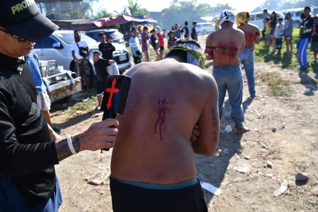 A man punctures the skin of penitents before flagillating themselves prior to the annual crucifixion during the observance of Lent in the village of Cutud in San Fernando City, Pampanga province on April 3, 2026. (Photo by Ted ALJIBE / AFP)