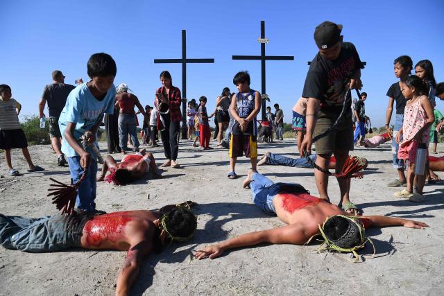TOPSHOT - Penitents prostrate themselves as companions flagellate their backs in front of the crosses prior to the annual crucifixion during the observance of Lent in the village of Cutud in San Fernando City, Pampanga province on April 3, 2026. (Photo by Ted ALJIBE / AFP)
