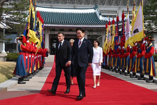 French President Emmanuel Macron (L), his wife Brigitte Macron (back C) and South Korean President Lee Jae Myung (C) and his wife Kim Hea Kyung (R) attend the welcome ceremony at the presidential Blue House in Seoul on April 3, 2026. (Photo by JUNG YEON-JE / POOL / AFP)