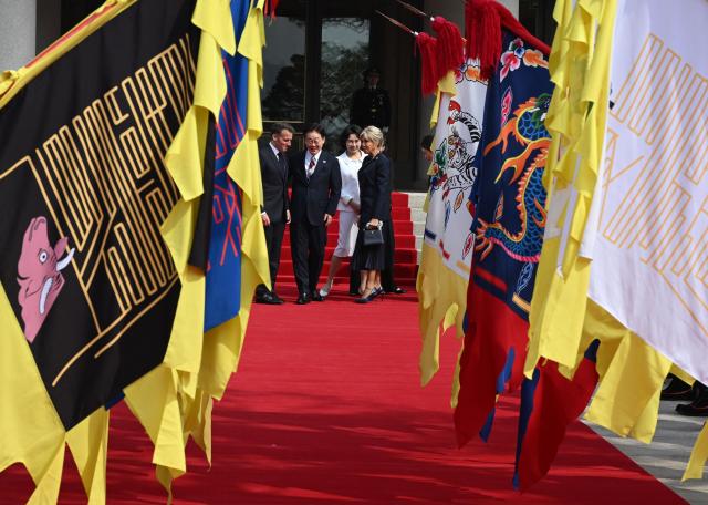 French President Emmanuel Macron (L), his wife Brigitte Macron (R) and South Korean President Lee Jae Myung (2nd L) and his wife Kim Hea Kyung (2nd R) attend the welcome ceremony at the presidential Blue House in Seoul on April 3, 2026. (Photo by JUNG YEON-JE / POOL / AFP)